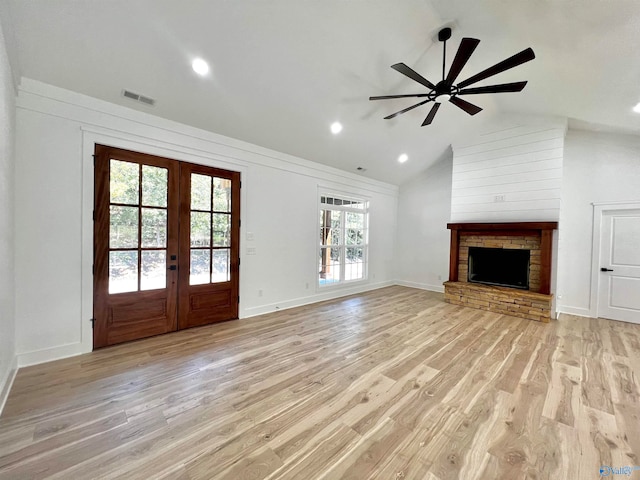 unfurnished living room featuring a stone fireplace, lofted ceiling, light hardwood / wood-style floors, and ceiling fan