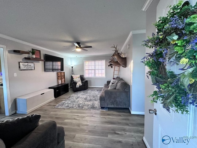 living room featuring ceiling fan, baseboards, wood finished floors, and ornamental molding