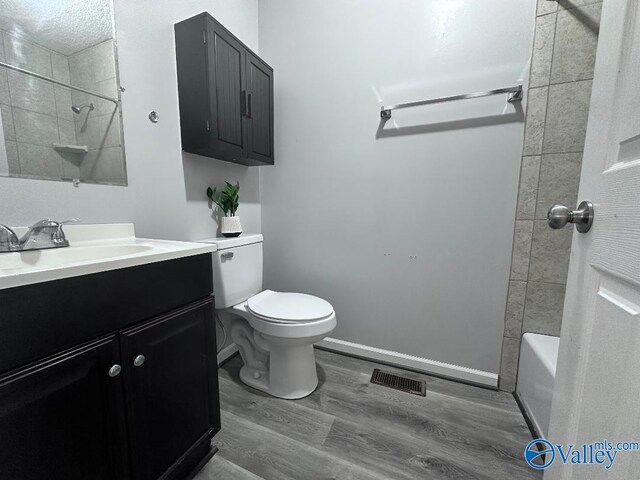 bathroom featuring visible vents, baseboards, toilet, wood finished floors, and vanity