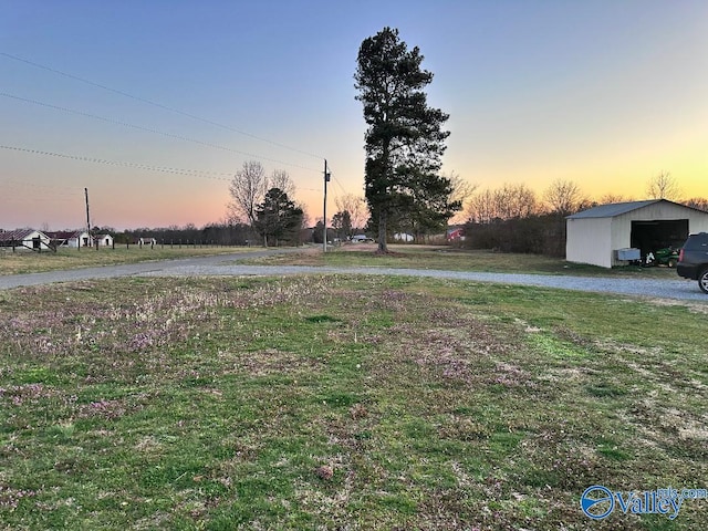 yard at dusk with a garage and an outdoor structure