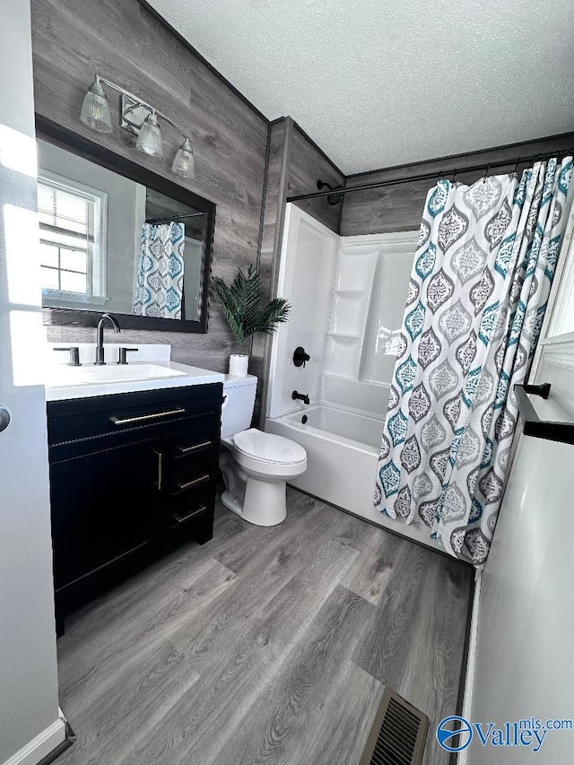 full bathroom with visible vents, shower / tub combo, wood finished floors, a textured ceiling, and vanity