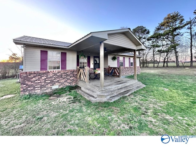 exterior space featuring a yard, ceiling fan, crawl space, brick siding, and metal roof