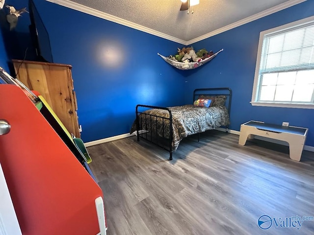 bedroom with a textured ceiling, wood finished floors, crown molding, baseboards, and ceiling fan