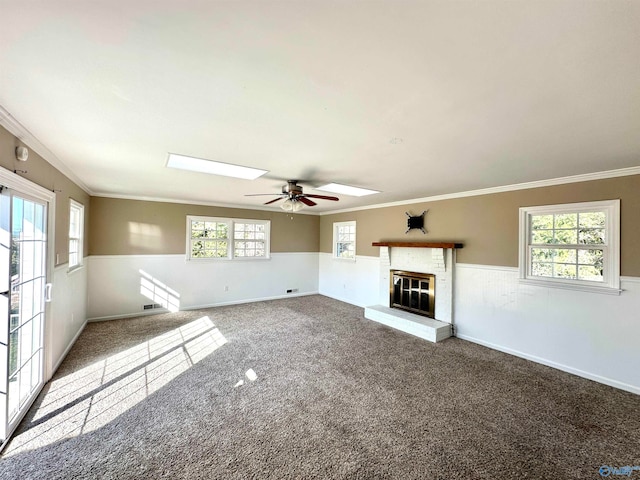 unfurnished living room featuring ornamental molding, carpet, a skylight, and ceiling fan