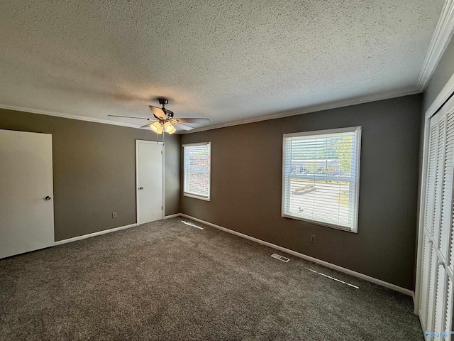 unfurnished bedroom featuring visible vents, ornamental molding, baseboards, a textured ceiling, and carpet flooring