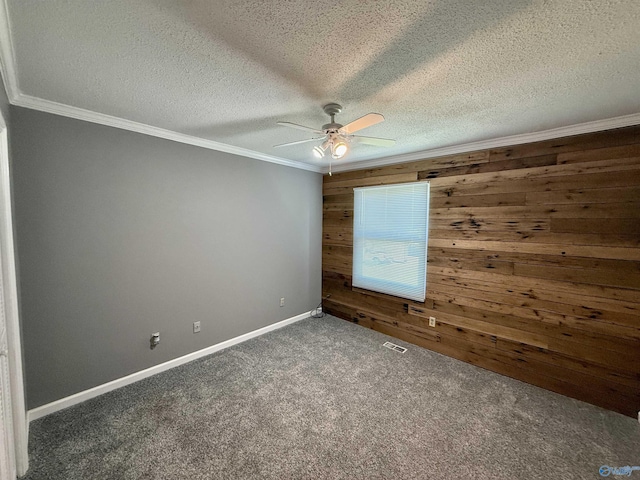 empty room with wooden walls, ceiling fan, carpet floors, ornamental molding, and visible vents