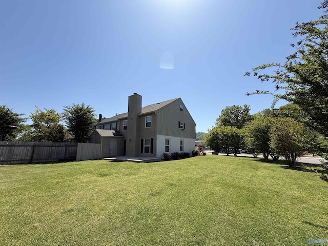exterior space with a lawn, fence, and a chimney