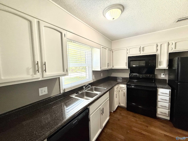 kitchen with a sink, a textured ceiling, black appliances, white cabinets, and visible vents