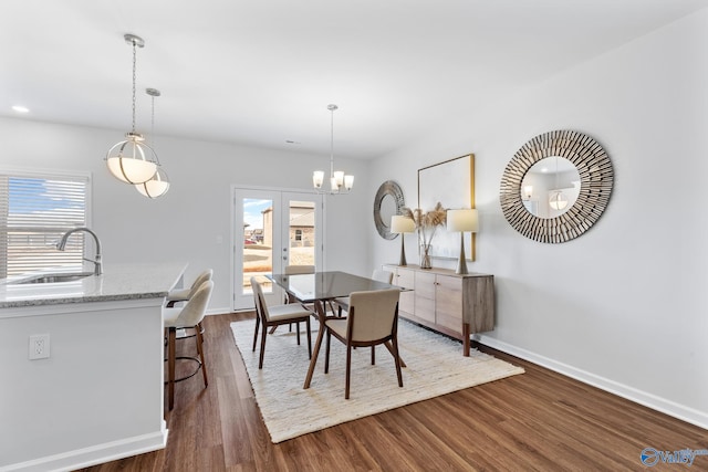 dining room featuring dark hardwood / wood-style floors, sink, a notable chandelier, and french doors