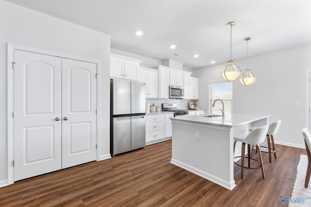 kitchen featuring stainless steel appliances, a center island with sink, and dark hardwood / wood-style flooring