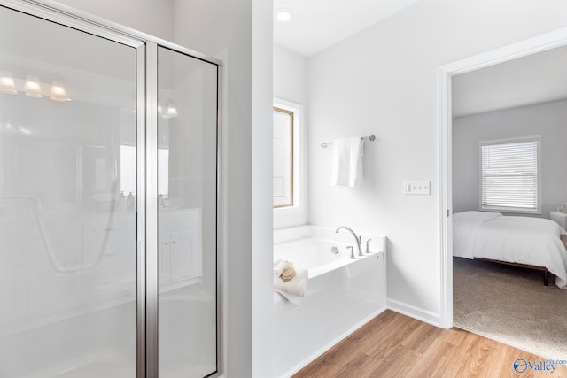 bathroom with a wealth of natural light, wood-type flooring, and separate shower and tub