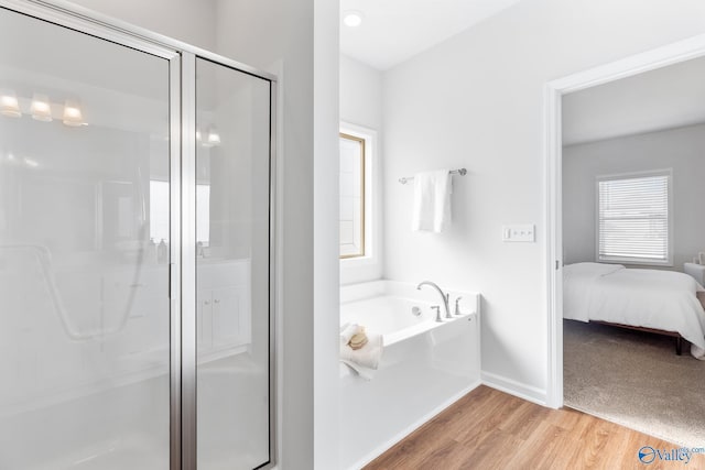 full bathroom featuring baseboards, wood finished floors, ensuite bathroom, a shower stall, and a bath