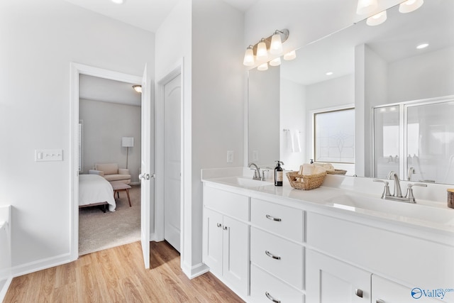 full bathroom featuring double vanity, connected bathroom, a sink, and wood finished floors