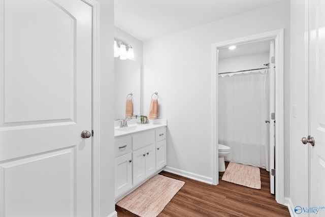 bathroom with hardwood / wood-style flooring, toilet, and vanity