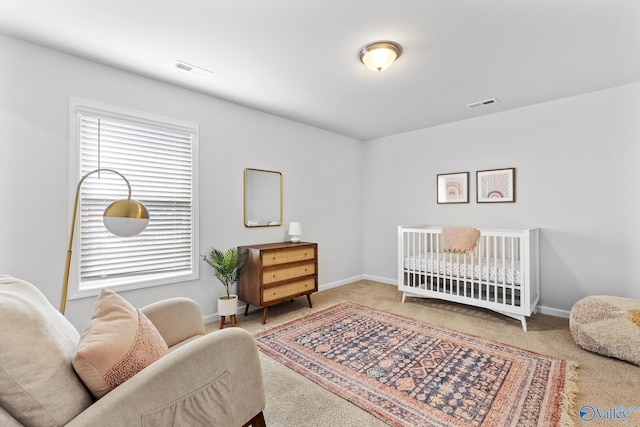 bedroom featuring light colored carpet and a nursery area