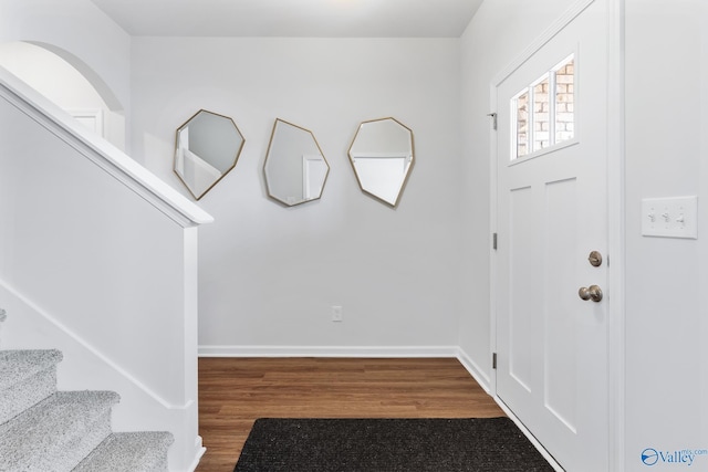 foyer entrance featuring dark wood-style floors, stairs, and baseboards