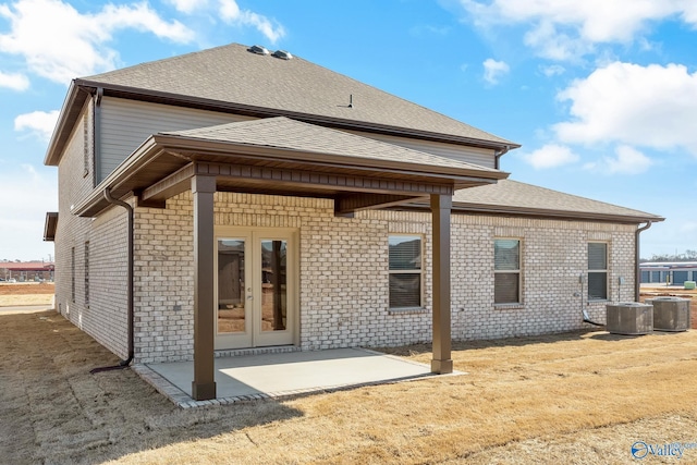 rear view of property with a patio area, a shingled roof, brick siding, and french doors