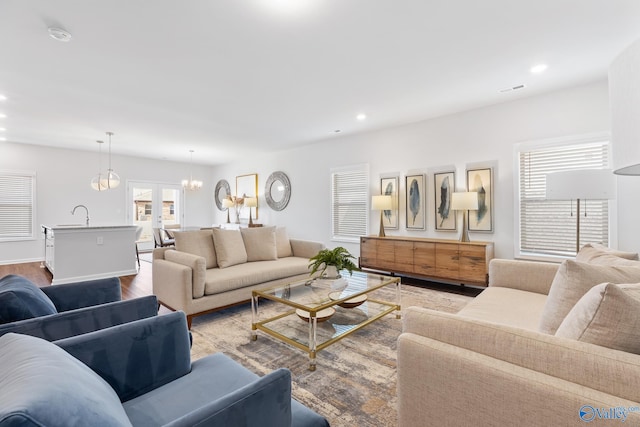 living room featuring sink, a notable chandelier, and light hardwood / wood-style flooring