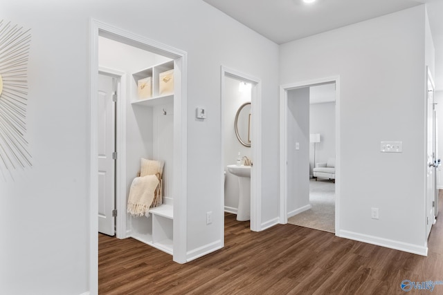 interior space with dark wood-type flooring, connected bathroom, and baseboards