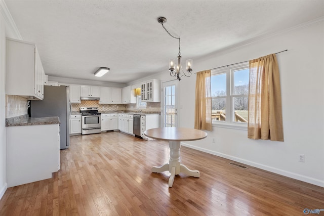 kitchen with tasteful backsplash, light wood finished floors, appliances with stainless steel finishes, a notable chandelier, and white cabinetry