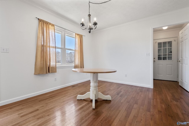 unfurnished dining area featuring visible vents, crown molding, baseboards, hardwood / wood-style floors, and a notable chandelier