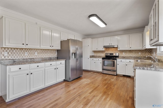 kitchen with under cabinet range hood, appliances with stainless steel finishes, light wood-style floors, white cabinetry, and a sink