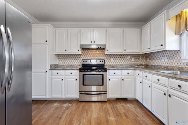 kitchen featuring range hood, appliances with stainless steel finishes, white cabinets, and a sink