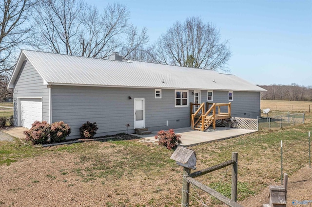 back of house featuring fence, metal roof, a wooden deck, a garage, and a chimney