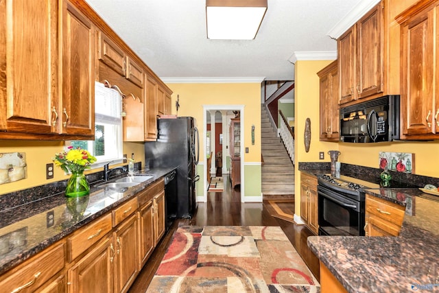 kitchen featuring dark wood-type flooring, sink, ornamental molding, dark stone counters, and black appliances