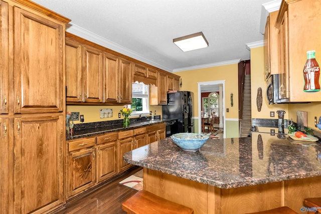 kitchen with ornamental molding, dark hardwood / wood-style floors, a kitchen breakfast bar, kitchen peninsula, and black appliances