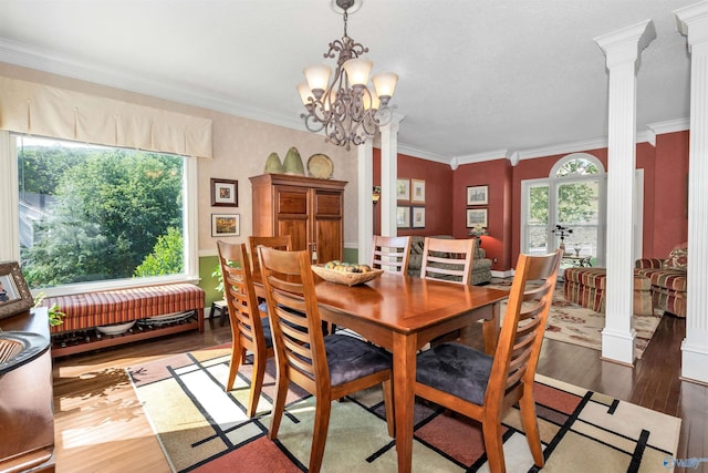 dining space featuring ornate columns, crown molding, dark hardwood / wood-style floors, and a healthy amount of sunlight