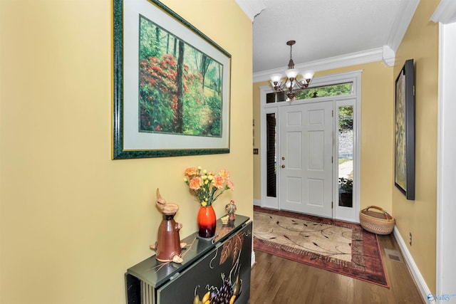 foyer with crown molding, dark hardwood / wood-style floors, and a chandelier