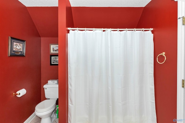 bathroom featuring tile patterned floors, toilet, vaulted ceiling, and a textured ceiling