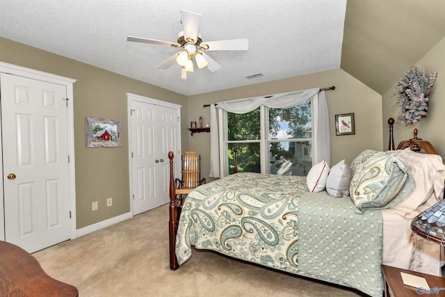 bedroom with vaulted ceiling, light carpet, a textured ceiling, and ceiling fan