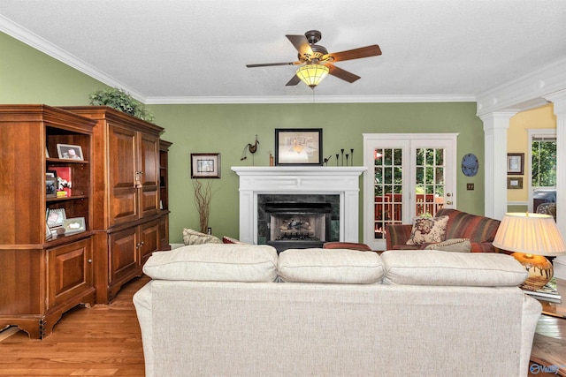 living room with ornate columns, ornamental molding, a high end fireplace, and light wood-type flooring