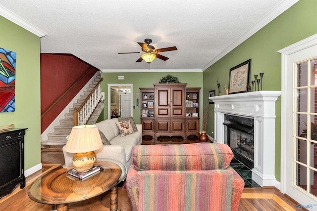 living room with crown molding, ceiling fan, a high end fireplace, and a textured ceiling