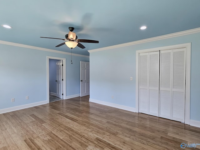 unfurnished bedroom featuring ornamental molding, hardwood / wood-style flooring, ceiling fan, and a closet