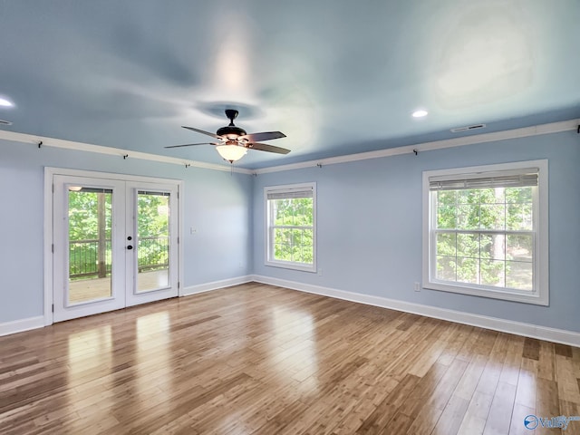 empty room featuring wood-type flooring, ceiling fan, french doors, and a healthy amount of sunlight