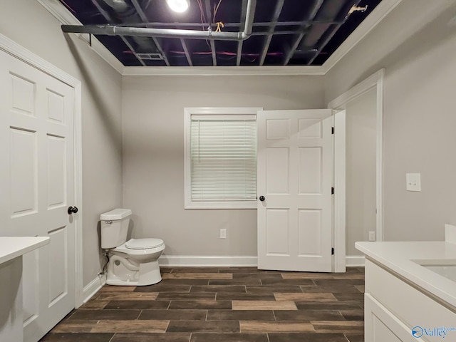 bathroom with ornamental molding, hardwood / wood-style flooring, vanity, and toilet