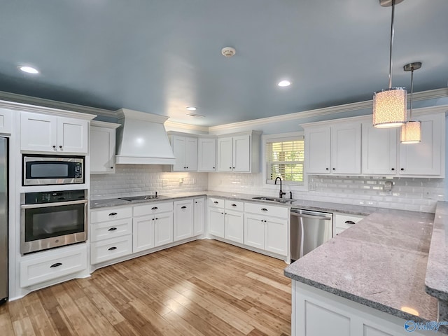 kitchen featuring appliances with stainless steel finishes, white cabinetry, sink, and custom exhaust hood