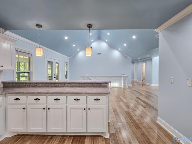 kitchen featuring white cabinets, lofted ceiling, decorative light fixtures, and light hardwood / wood-style flooring