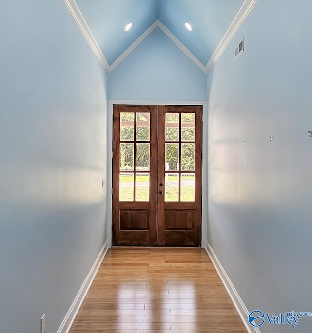 doorway featuring french doors, ornamental molding, vaulted ceiling, and light wood-type flooring