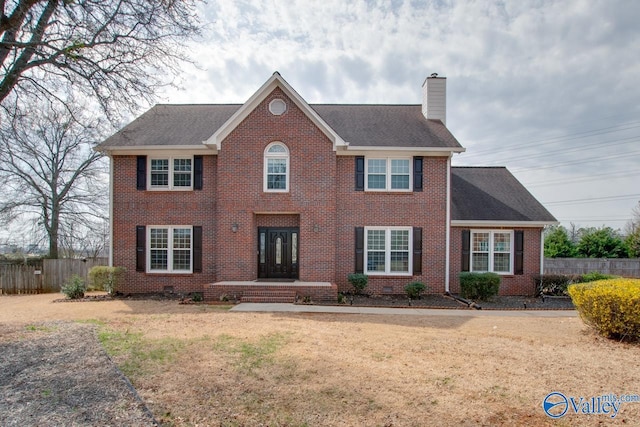 colonial-style house with crawl space, a chimney, brick siding, and fence