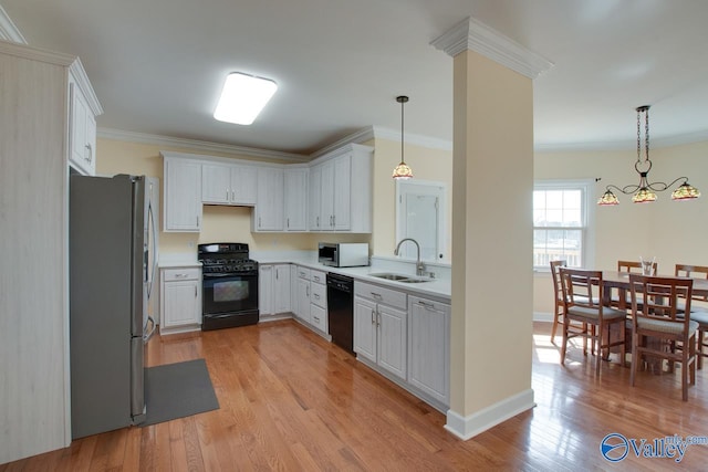 kitchen with a sink, light wood-type flooring, black appliances, and crown molding