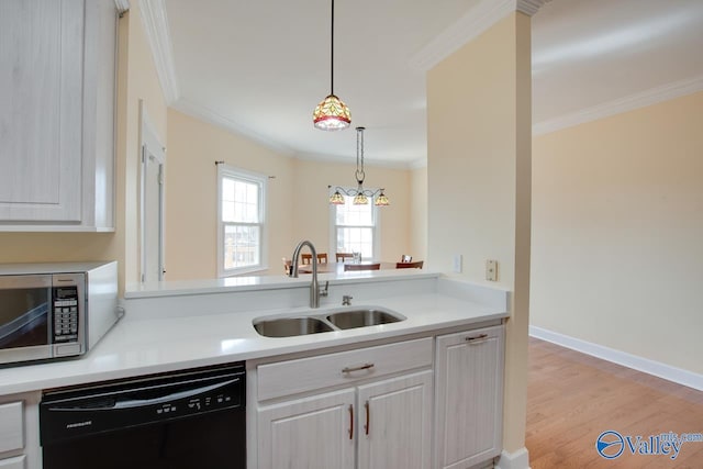 kitchen featuring stainless steel microwave, crown molding, dishwasher, light countertops, and a sink