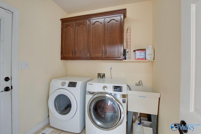 laundry room with cabinet space, washer and dryer, baseboards, and a sink