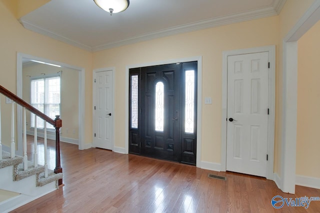 foyer entrance with stairway, wood finished floors, visible vents, and ornamental molding