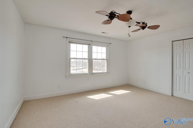 empty room featuring visible vents, baseboards, a textured ceiling, and carpet flooring