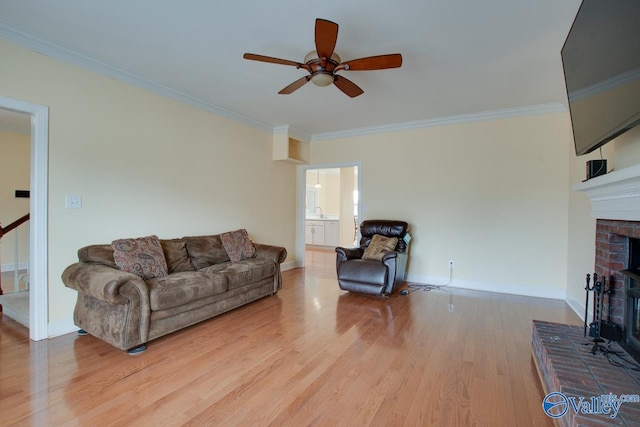 living room with baseboards, light wood-style floors, ornamental molding, and a fireplace