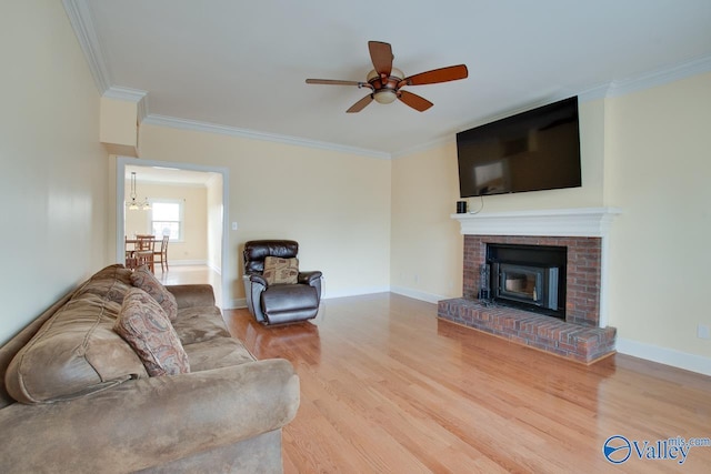 living area with a brick fireplace, wood finished floors, baseboards, and ornamental molding